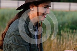 Defocus smiling young woman in cowboy hat. Girl in a cowboy hat in a field. Nature background. Closeup portrait
