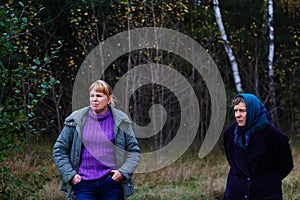 Defocus two woman standing in pine forest. Leisure and people concept, mother and daughter in fall forest. People lost