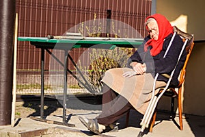 Defocus ukrainian elderly woman in red shawl with crutches sleeping outside. Woman 90 years old. Sick and homecare. Out