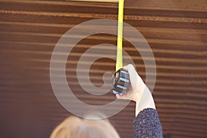 Defocus woman construction worker measures plasterboard ceiling with tape measure. Female hands making window