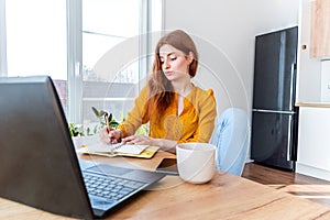 Defocus. Young woman teaches English online on the Internet using a computer. Female freelancer is browsing in a laptop