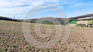 Defocused abstract background of farmfield and blue sky with clouds. Plain landscape background