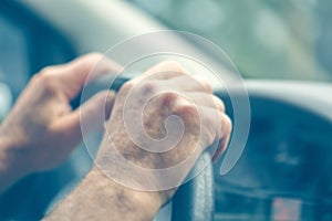 Defocused background of the driver`s hand with blue toning. Male hands on the steering wheel driving a car Driving a car