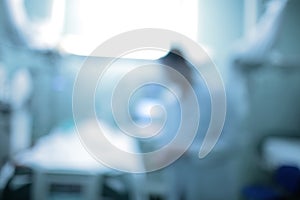 Defocused background with female doctor silhouette standing at the patient bed in the critical care unit