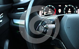 Defocused backlight of LED dashboard behind car steering wheel with heating and voice control buttons on it