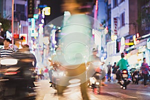 Defocused blurry scene of the night street with blurry motorbike traffic, pedestrians, signboards and all sorts of neon lights