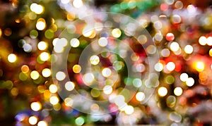 Defocused bright ligths of decorated Christmas tree in the rural house interior. Blurred New year festive background.