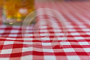 Defocused glass of beer on a chequered tablecloth