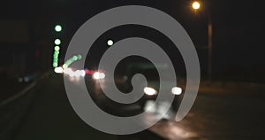 Defocused headlights and tail lights of approaching highway traffic shine during rush hour. Night shot of busy overpass