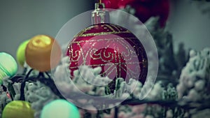 Defocused holiday lights of Christmas garland glowing about ornate red ball. Christmas video background