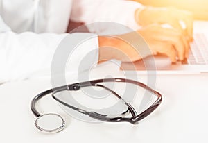 Defocused image of a doctor working with laptop computer in medical workspace office as concept with stethoscope
