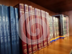 Defocused image. Multi-colored books on the bookshelf in the library. The bokeh effect