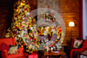 Defocused image. Red and gold decorations on a Christmas tree in a room with an armchair and a fireplace. blurry background photo