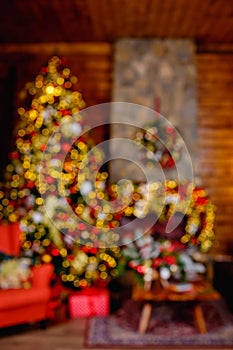 Defocused image. Red and gold decorations on a Christmas tree in a room with an armchair and a fireplace. blurry background photo