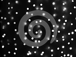 Defocused lights of Christmas garland in black and white evenly distributed over the area of the frame, background, texture