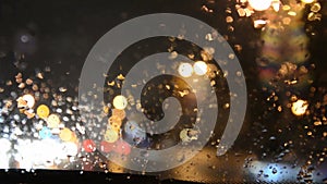 Defocused lights. Driving on a rainy highway, cars braking. Rain on windshield.