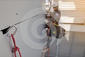Defocused rope access wearing full safety body harness removing wall panel with secured Carabiner rope preventing from drop object