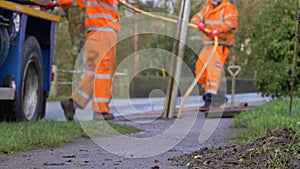 Defocused Shot of Drainage Workers Reeling In Hose from Drain In Flooded Village. High quality