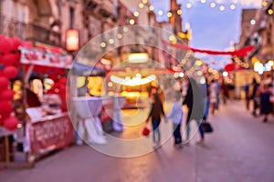 Defocused silhouette of family during Christmas fair an town street with colorful Christmas lights