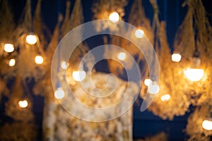 Defocused of sofa, dry yellow flowers and light bulb hanging.