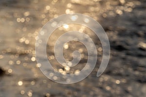 The defocused view of fresh river stream water slowly flowing through natural rock beach in the morning. Abstract nature