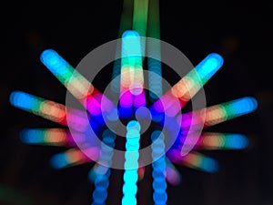 Defocused view of the lower part of a drop tower with colorful structure in the dark at Wurstelprater in Vienna, Austria.