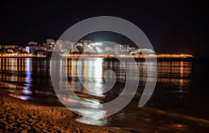 Defocused winter landscape. Cloudy night view of the bright lights of the buildings and the city center of the resort of