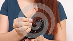 Defocused woman stretches out her hands to camera and shows large amount of hair that has fallen out. Alopecia.