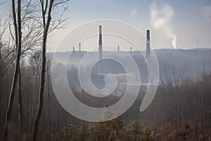 deforested landscape with towering smoke stacks from nearby coal plant