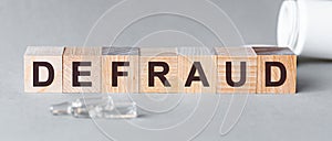 Defraud is a word written in black letters on wooden cubes photo