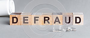 Defraud is a word written in black letters on wooden cubes photo