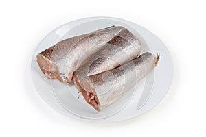 Defrosted uncooked Argentine hake carcasses on a white dish