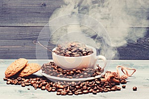 Degree of roasting grain. Cup full coffee brown roasted beans white clouds of smoke blue wooden background. Cafe drinks