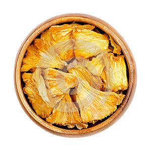 Dehydrated pineapple pieces, chunks of dried fruits, in a wooden bowl