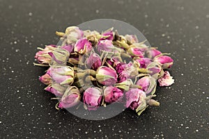 Dehydrated pink rose buds on a black cutting board