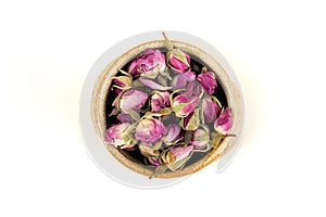 Dehydrated pink rose buds in a ceramic bowl top down view