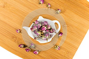 Dehydrated pink rose buds in a tea plate on a cutting board
