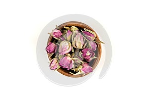 Dehydrated pink rose buds top down view in a small wooden bowl