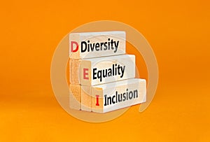 DEI diversity equality inclusion symbol. Concept words DEI diversity equality inclusion on blocks. Beautiful orange background.