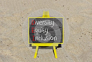 DEI diversity equity and inclusion symbol. Concept words DEI diversity equity inclusion on blackboard. Beautiful sand background.