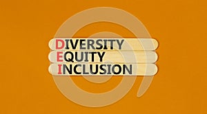 DEI diversity equity and inclusion symbol. Concept words DEI diversity equity inclusion on stick. Beautiful orange background.