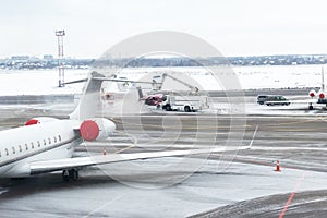 Deicing of private jet before departure at airport in winter. Aircraft protection against freezing . Process of covering passenger