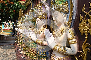 Deity statues standing in a row on a temple wall in Thailand