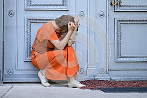 Dejected woman crouching in front of a historic entrance door