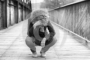Dejected woman squatting on a bridge