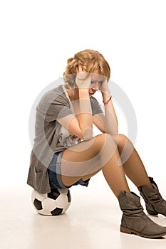 Dejected young woman sitting on a soccerball