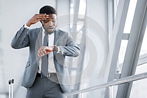 Delayed Flight. Businessman Looking At Watch At Airport