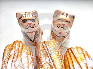 Delectable Dessert Pastries With Charming Porcelain Cat Figurines. Piped cakes sprinkled with sugar beside whimsical cat photo