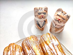 Delectable Dessert Pastries With Charming Porcelain Cat Figurines. Piped cakes sprinkled with sugar beside whimsical cat photo