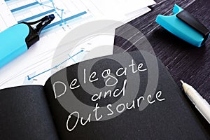 Delegate and Outsource written on a page. Delegation cincept